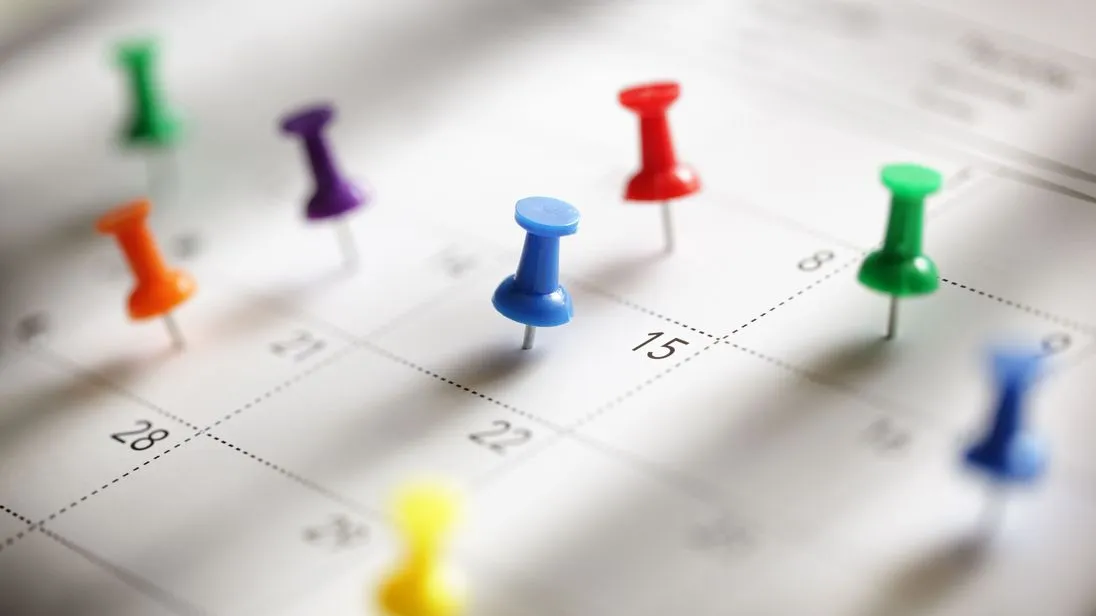 Ein Kalender auf den Stecknadeln in verschiedenen Farben gepinnt sind.