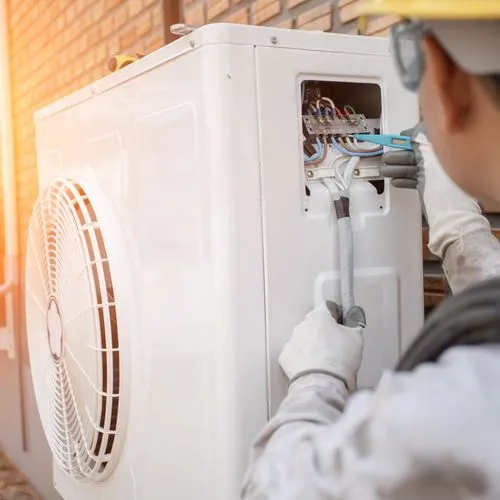 Ein Handwerker montiert eine Wärmepumpe.