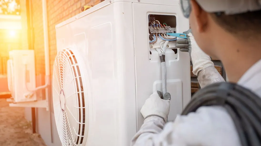Ein Handwerker montiert eine Wärmepumpe.