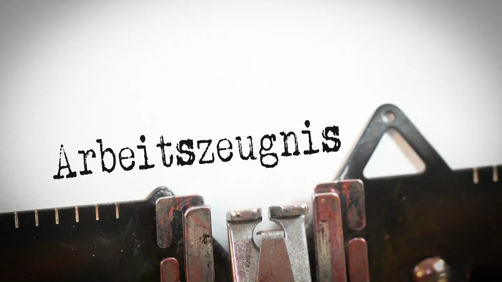 Ein gräulicher Hintergrund auf dem "Arbeitszeugnis" steht. Darunter ist ein Werkzeug zum Messen.