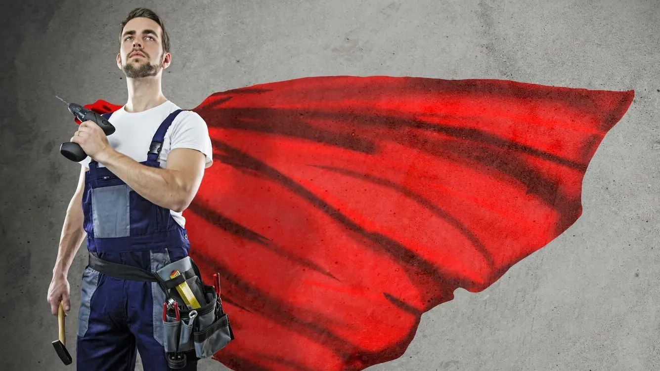 Ein Handwerker in Latzhose schaut arrogant. Der Hintergrund ist eine graue Wand und darauf verteilte rote Farbe. Es sieht aus als hätte der Handwerker einen roten Umhang an, wie Superman.