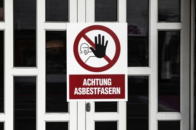 Weiße Haustür auf der ein Warnschild angebracht ist. Dort steht: "Achtung Asbestfasern".