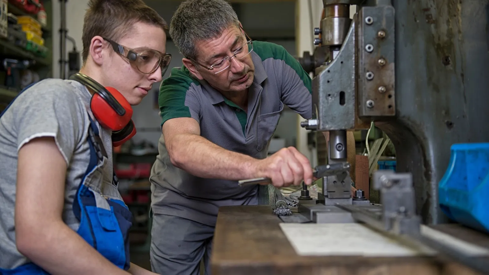 Ausbilder und Azubi im Handwerk an einer Maschine