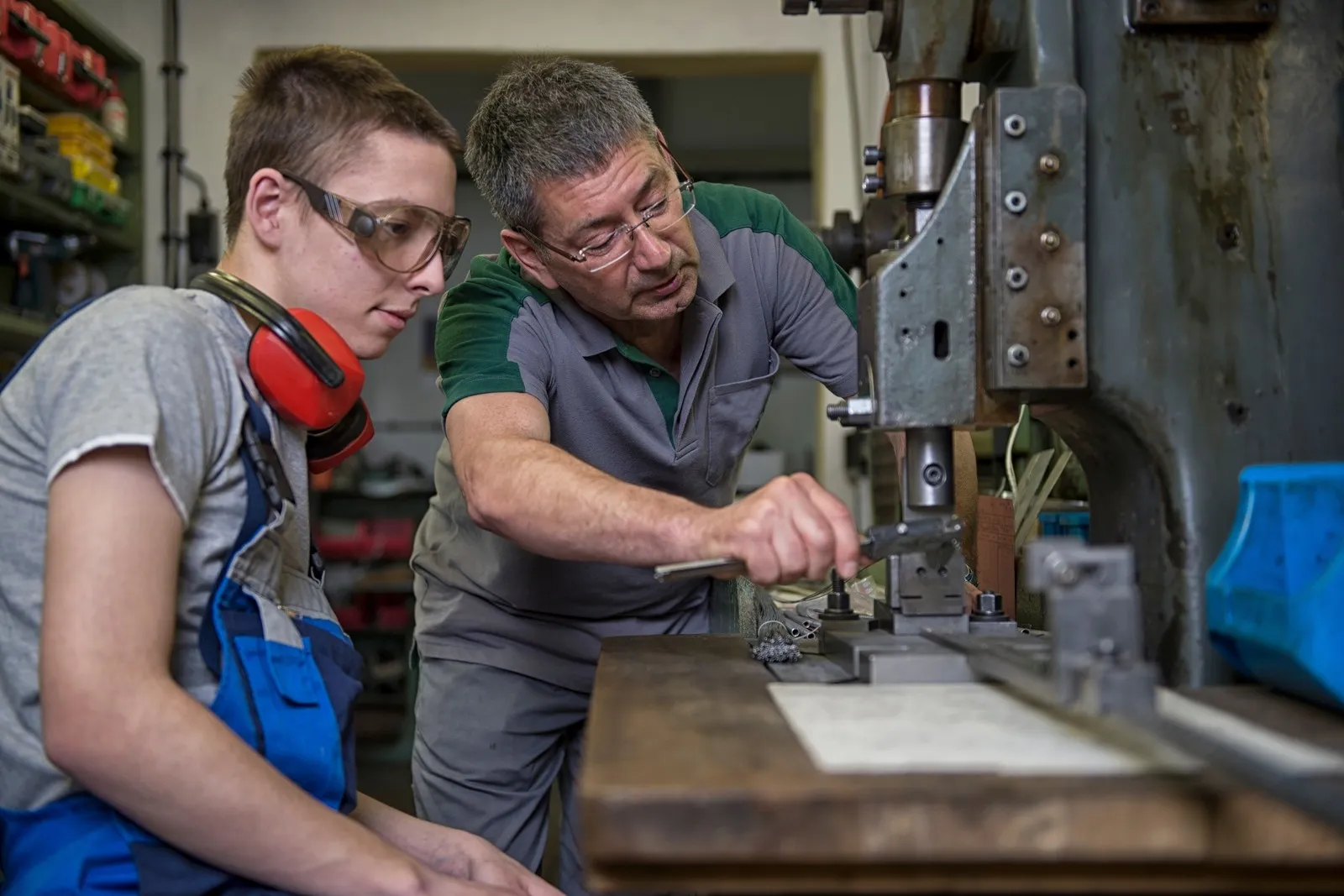 Ausbilder und Azubi im Handwerk an einer Maschine