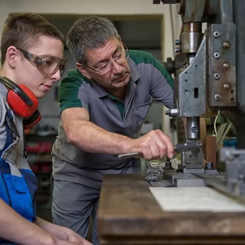 Ausbilder und Azubi im Handwerk an einer Maschine