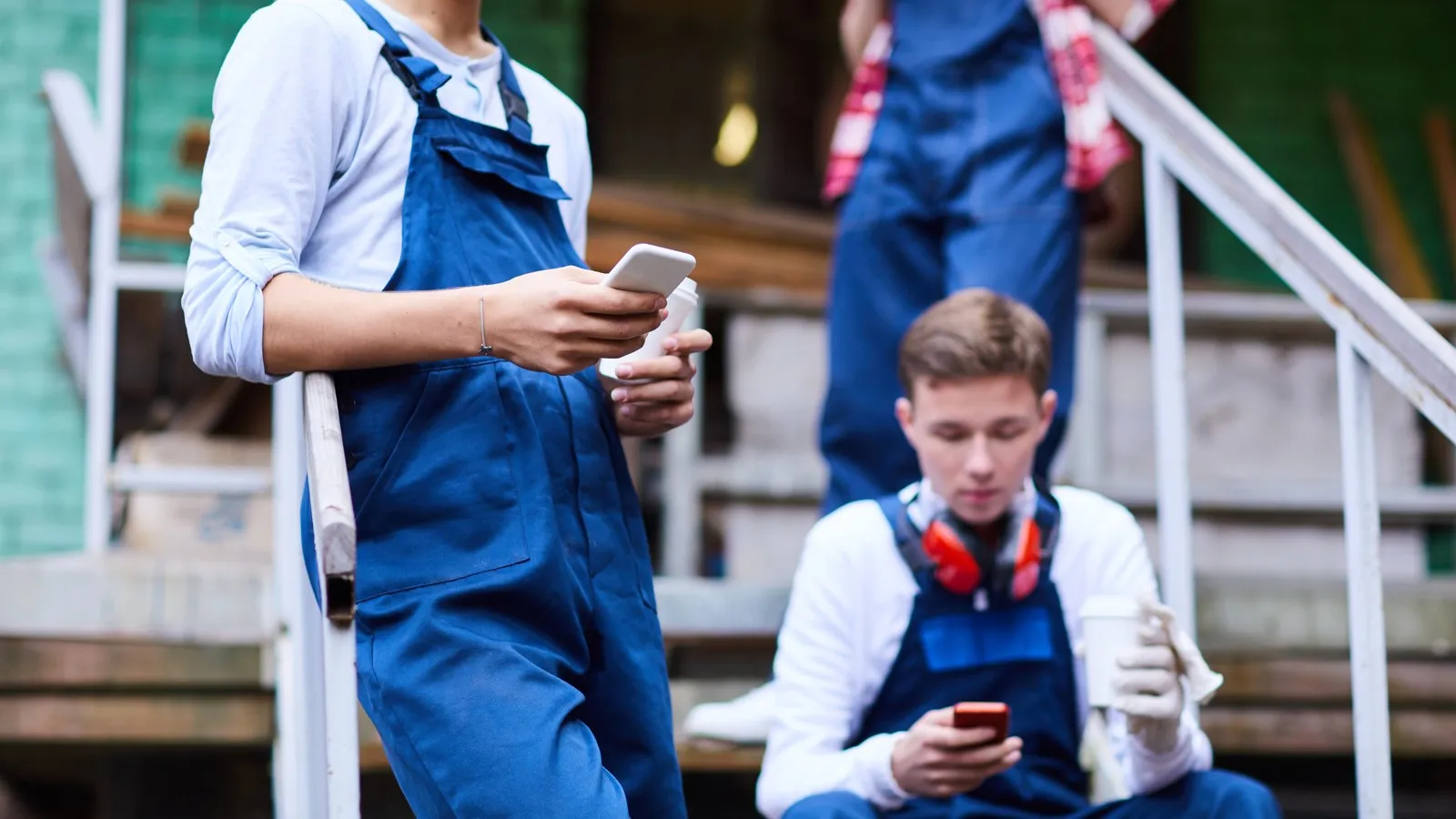 Auszubildende im Handwerk machen Pause und schauen auf ihr Handy