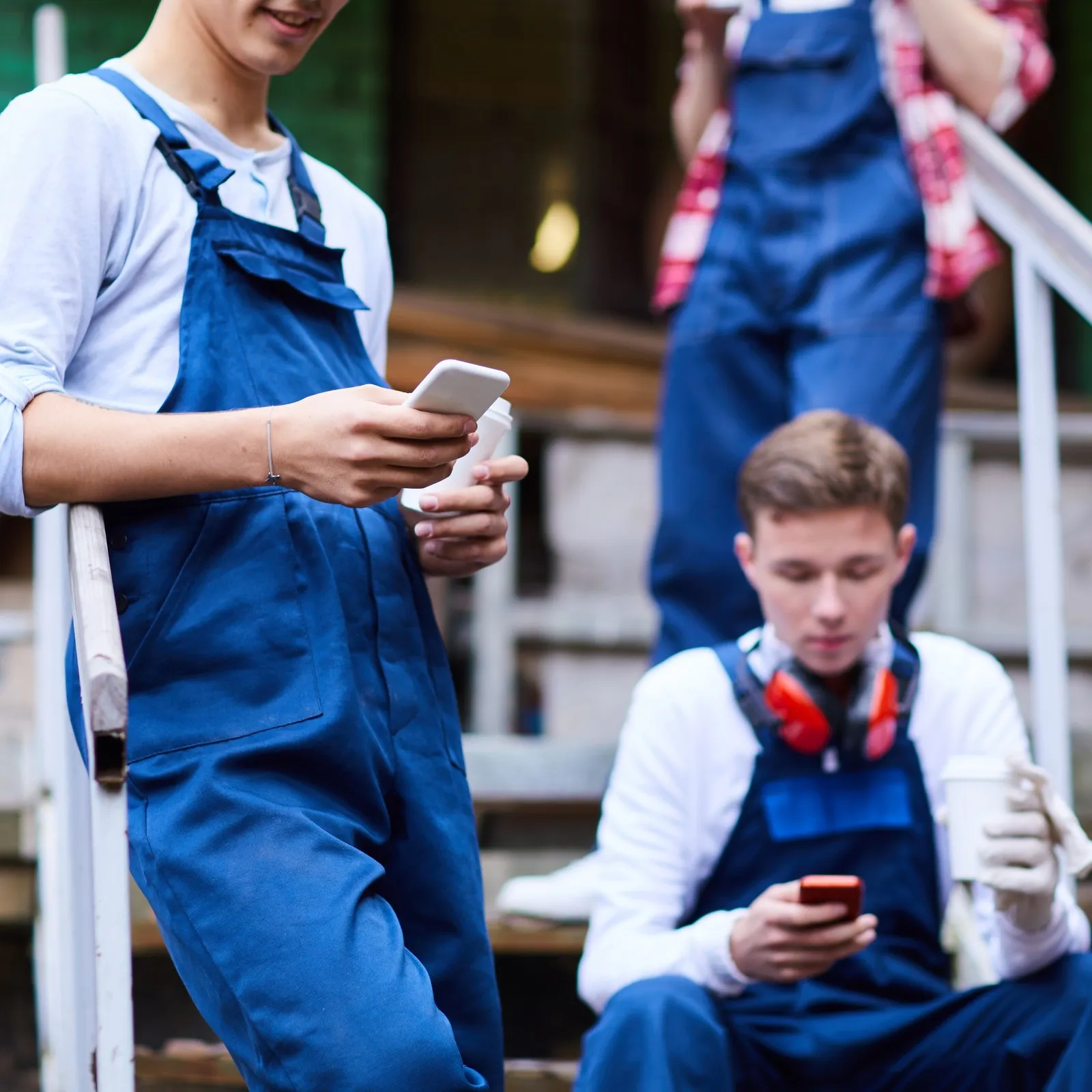Auszubildende im Handwerk machen Pause und schauen auf ihr Handy