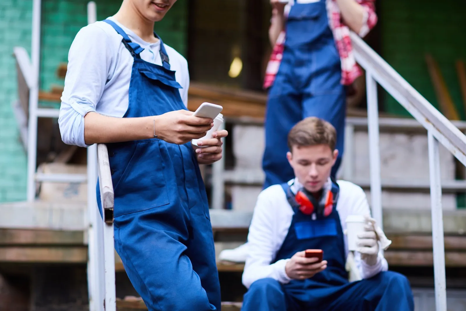 Auszubildende im Handwerk machen Pause und schauen auf ihr Handy