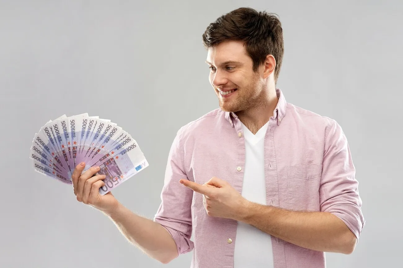 Ein Mann hält in seiner Hand mehrere 500 Euro Scheine und zeigt mit dem Zeigefinger darauf.