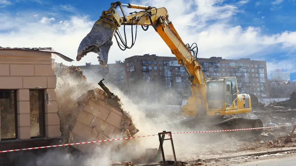 Bagger auf der Baustelle beim Abbruch in einer Staubwolke.