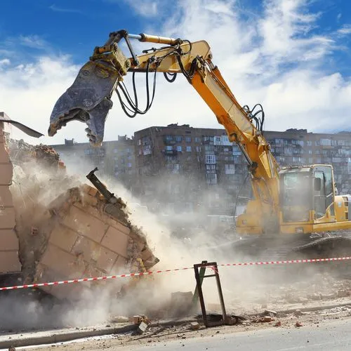 Bagger auf der Baustelle beim Abbruch in einer Staubwolke.