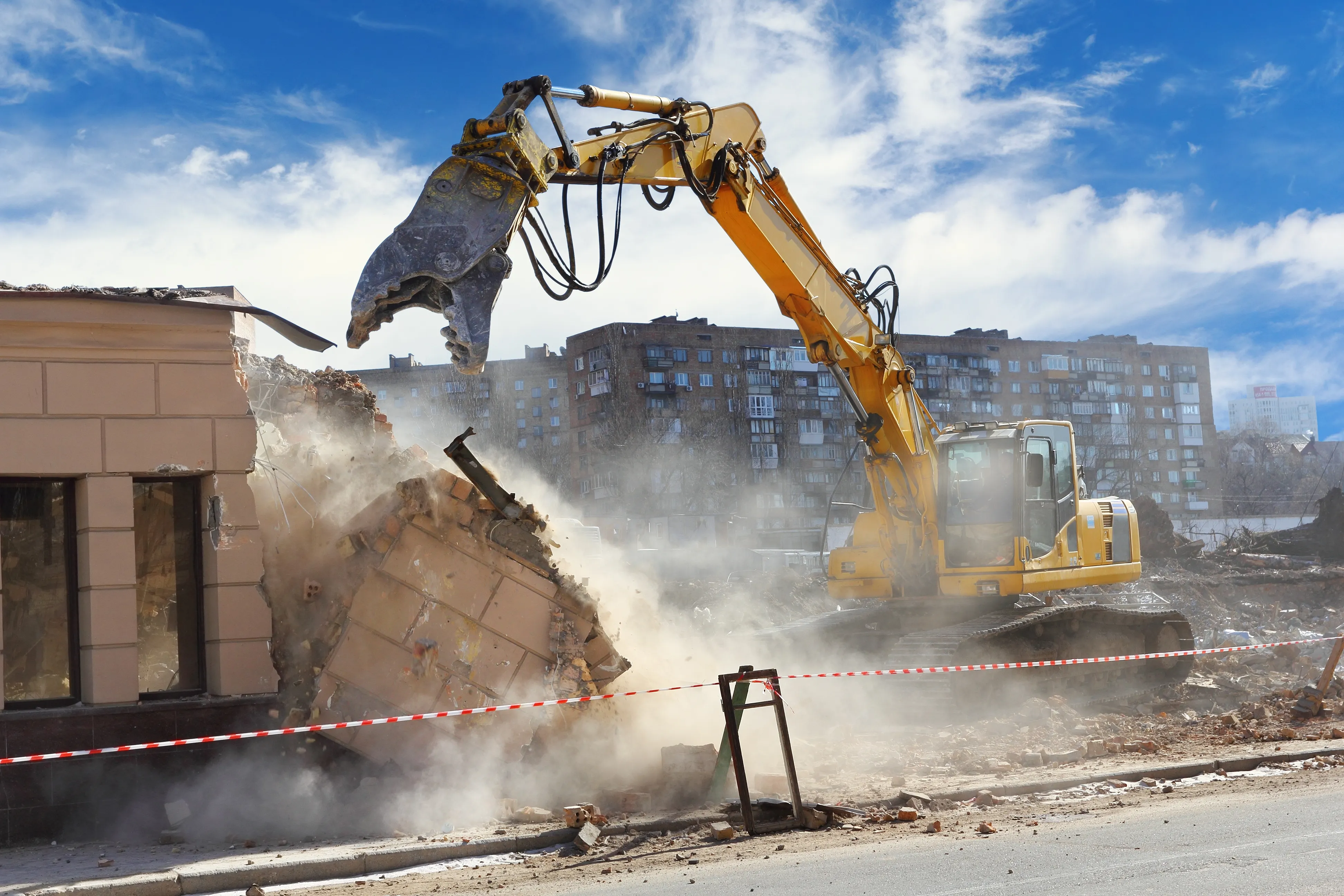 Bagger auf der Baustelle beim Abbruch in einer Staubwolke.