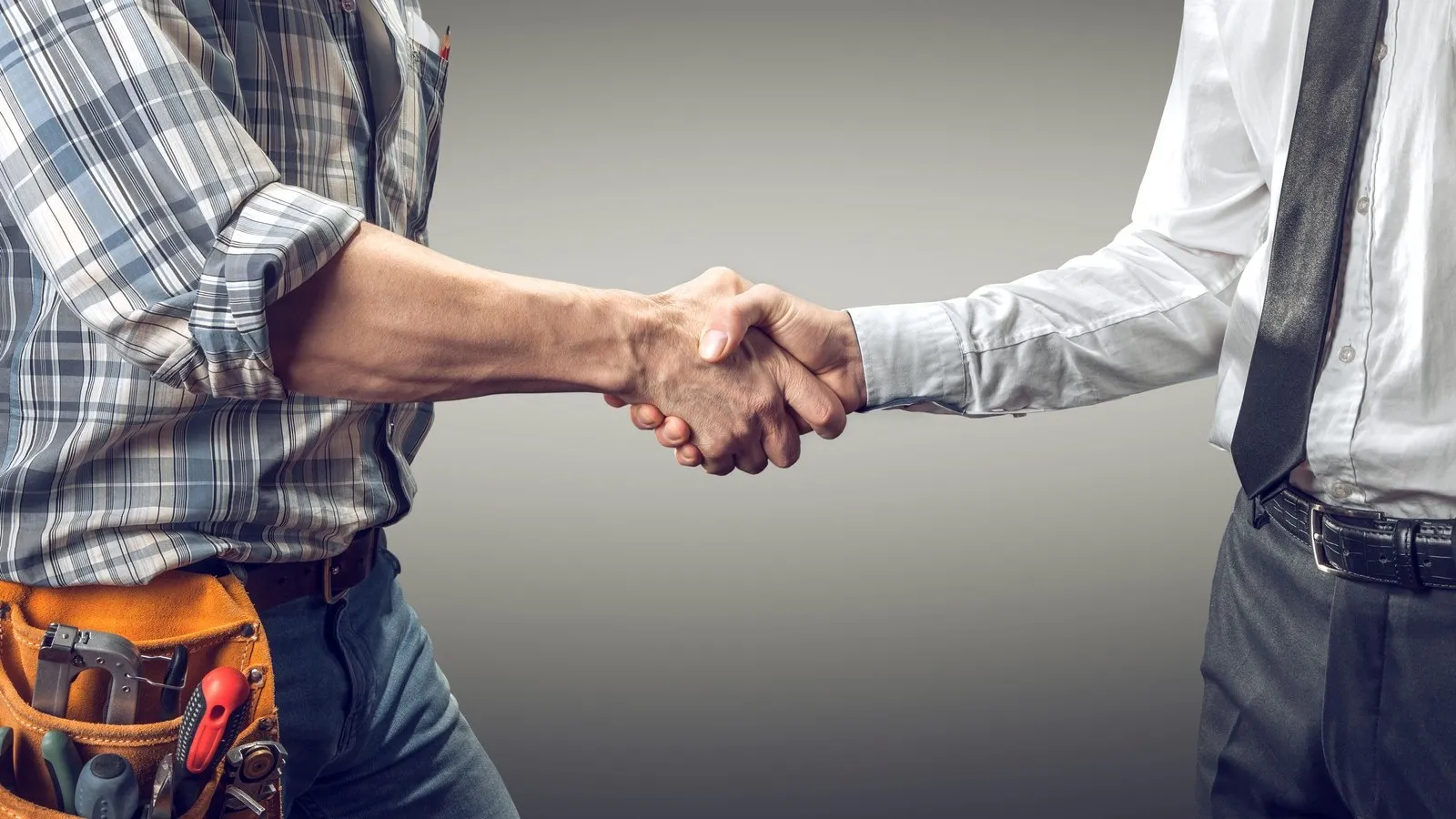 Handwerker und Bauherr schütteln sich die Hand.
