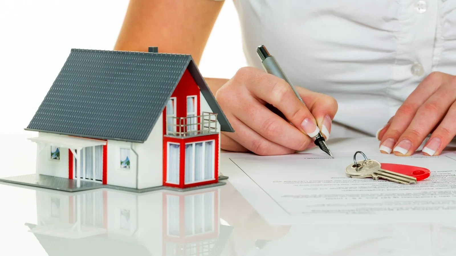Eine Frau unterschreibt einen Kaufvertrag für ein Haus bei einem Immobilienmakler.