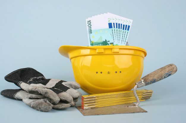 100 Euro-Scheine liegen in einem Bauhelm - mit Werkzeugen daneben.