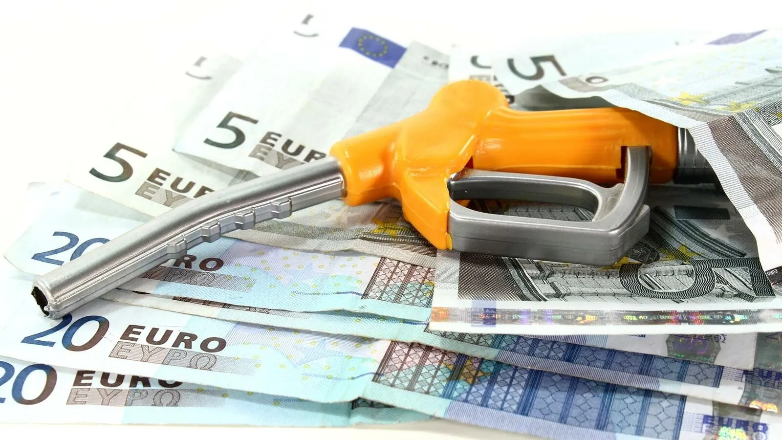Mehrere 5 und 20 Euro Scheine liegen halb aufeinander, darauf liegt sich eine Zapfpistole.