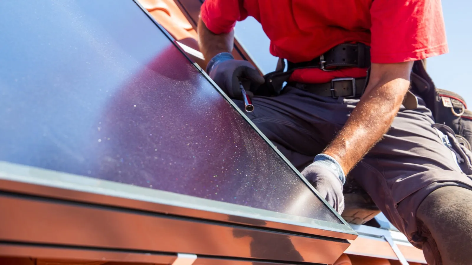 Ein Handwerker installiert ein Solarmodul auf dem Dach.
