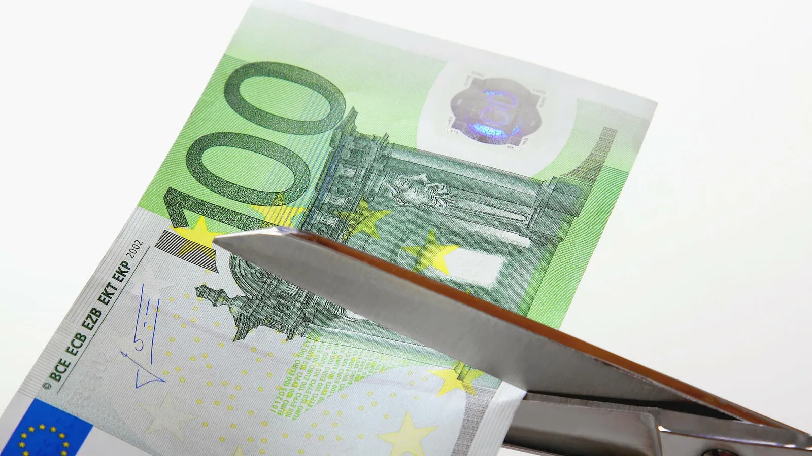 Schere zerschneidet Geldschein