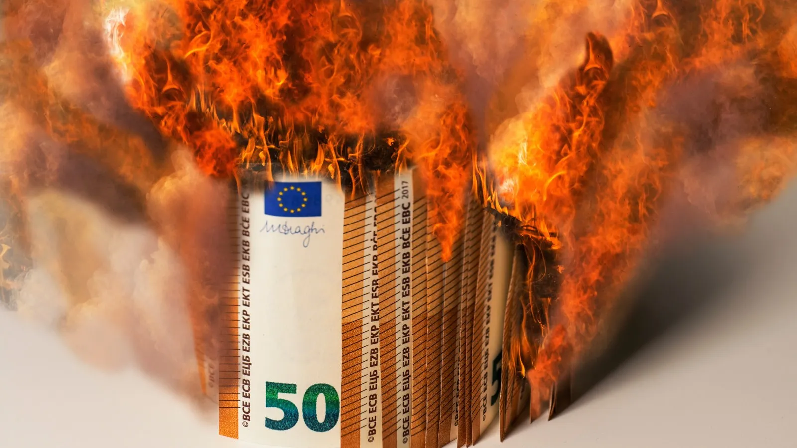Ein Gelbündel an 50 Euro Scheinen steht in Flammen.