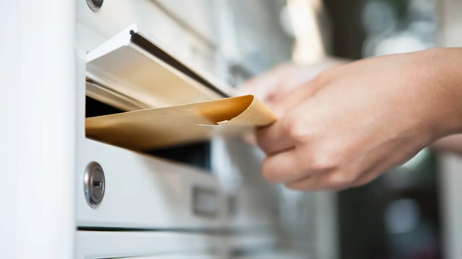 Ein Brief wird in den Briefkasten gesteckt.