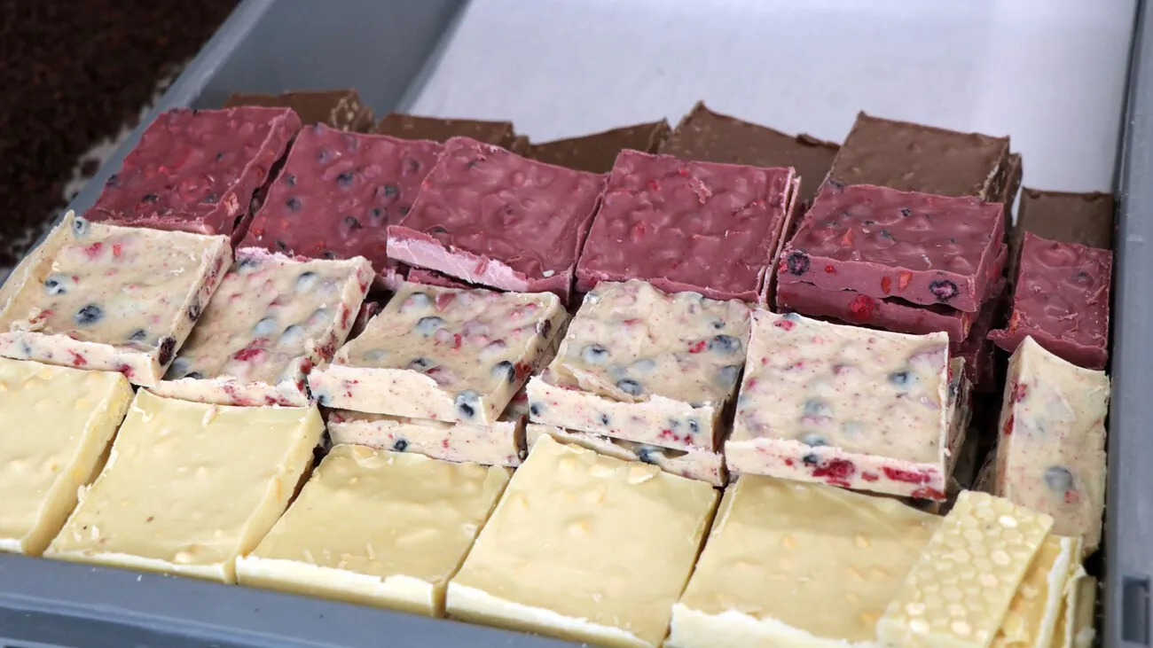 Bruchschokolade aus weißer, rubinroter und Zartbitterschokolade veredelt der Konditormeister mit Nüssen und Früchten.