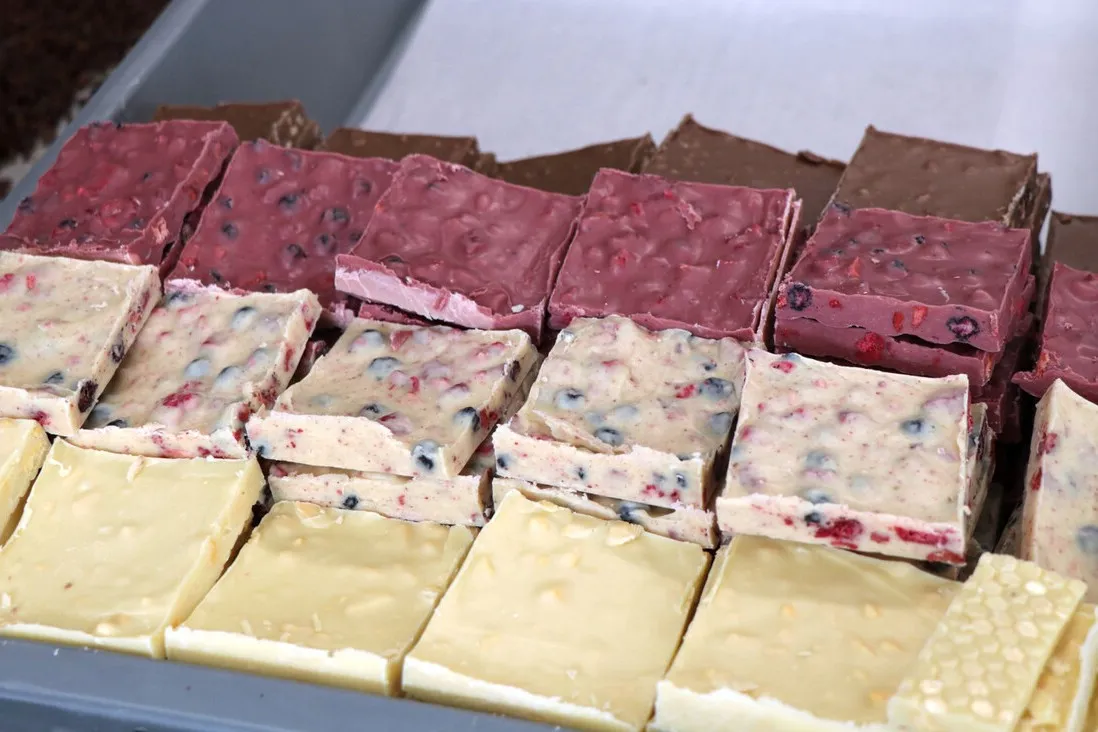 Bruchschokolade aus weißer, rubinroter und Zartbitterschokolade veredelt der Konditormeister mit Nüssen und Früchten.