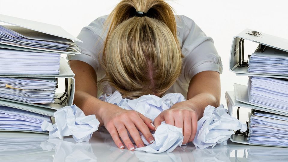 Junge Frau im Büro ist mit der Arbeit überfordert. Burnout bei Arbeit oder Studium.
