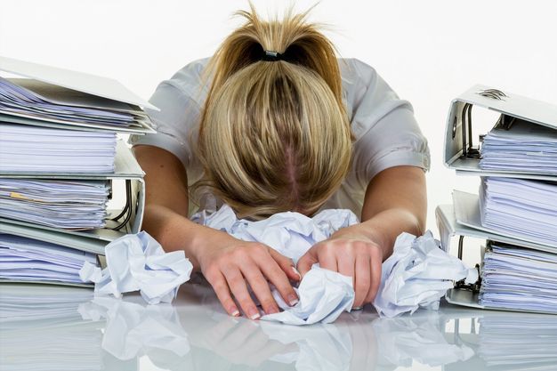 Junge Frau im Büro ist mit der Arbeit überfordert. Burnout bei Arbeit oder Studium.