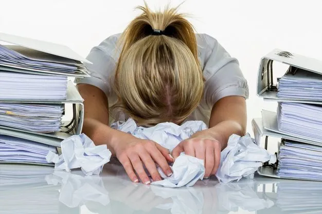Junge Frau im Büro ist mit der Arbeit überfordert. Burnout bei Arbeit oder Studium.