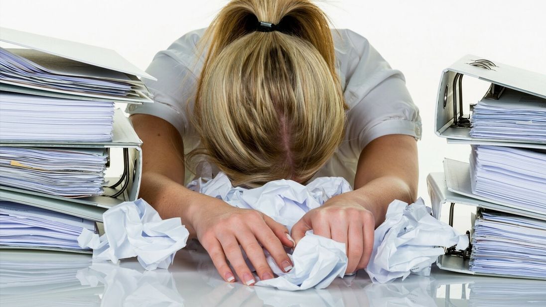 Junge Frau im Büro ist mit der Arbeit überfordert. Burnout bei Arbeit oder Studium.