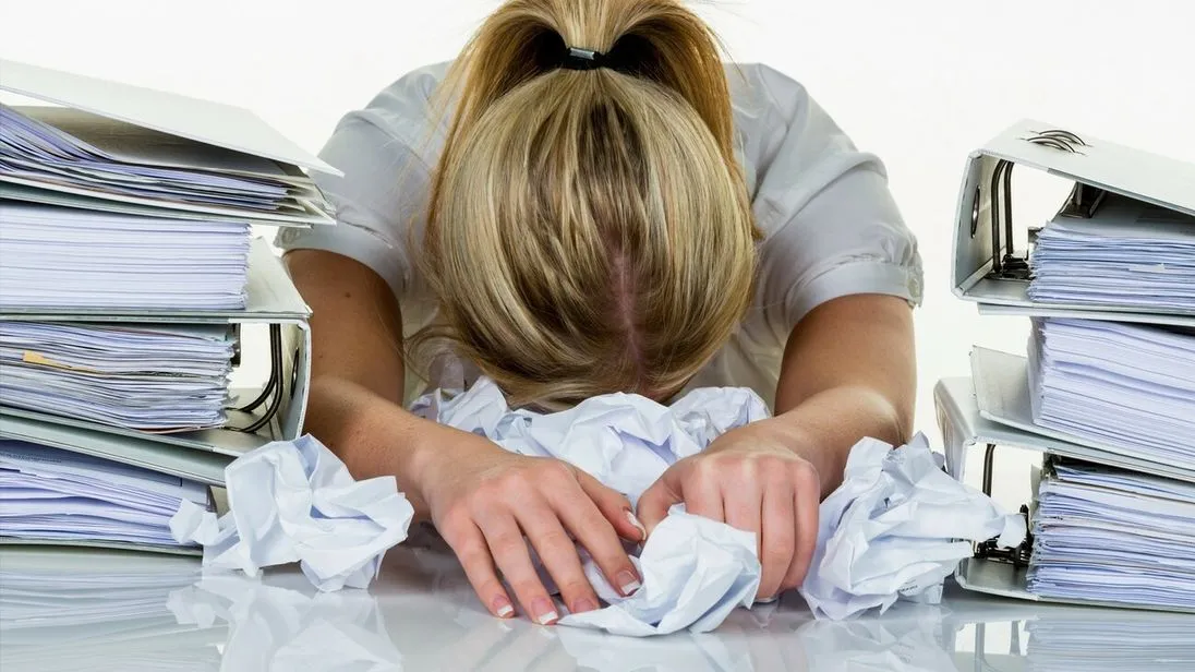 Junge Frau im Büro ist mit der Arbeit überfordert. Burnout bei Arbeit oder Studium.