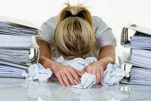 Junge Frau im Büro ist mit der Arbeit überfordert. Burnout bei Arbeit oder Studium.