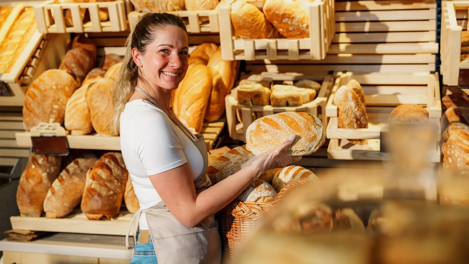 Eine verkäufrein bietet in einer Bäckerei frisches Brot an.