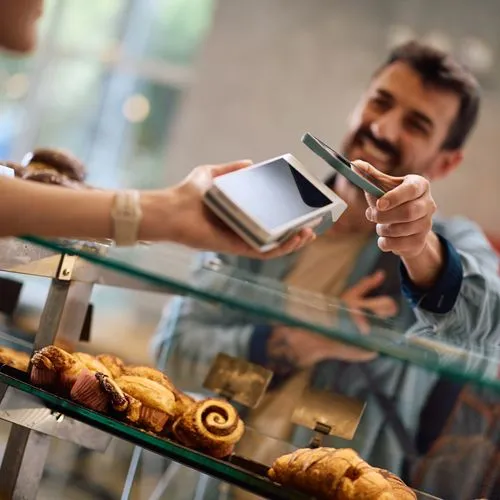 ein kunde zahlt per handy in einer bäckerei