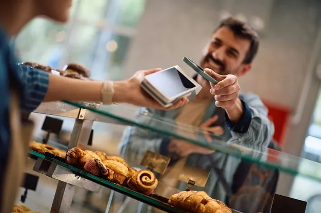ein kunde zahlt per handy in einer bäckerei