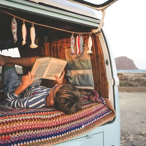 Junge liest ein Buch  in einem Camper.