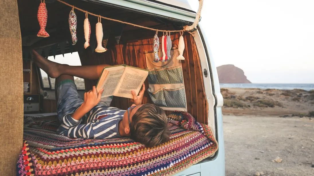 Junge liest ein Buch  in einem Camper.