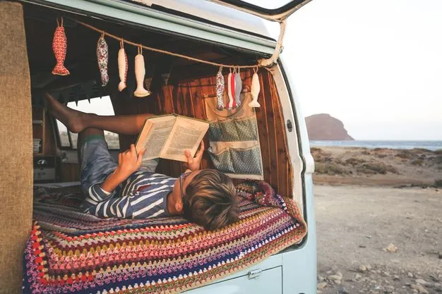 Junge liest ein Buch  in einem Camper.