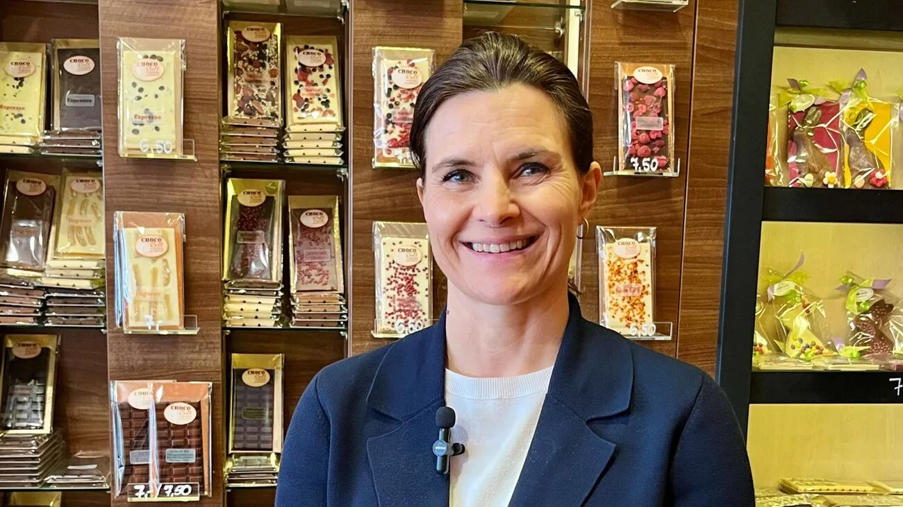 Tafelschokoladen, Eis und Pralinen verkaufen die Mangolds in einem kleinen Raum neben dem Café. Konditormeisterin Cornelia Mangold vor der Wand, die nur einen Teil des Angebots abbildet.