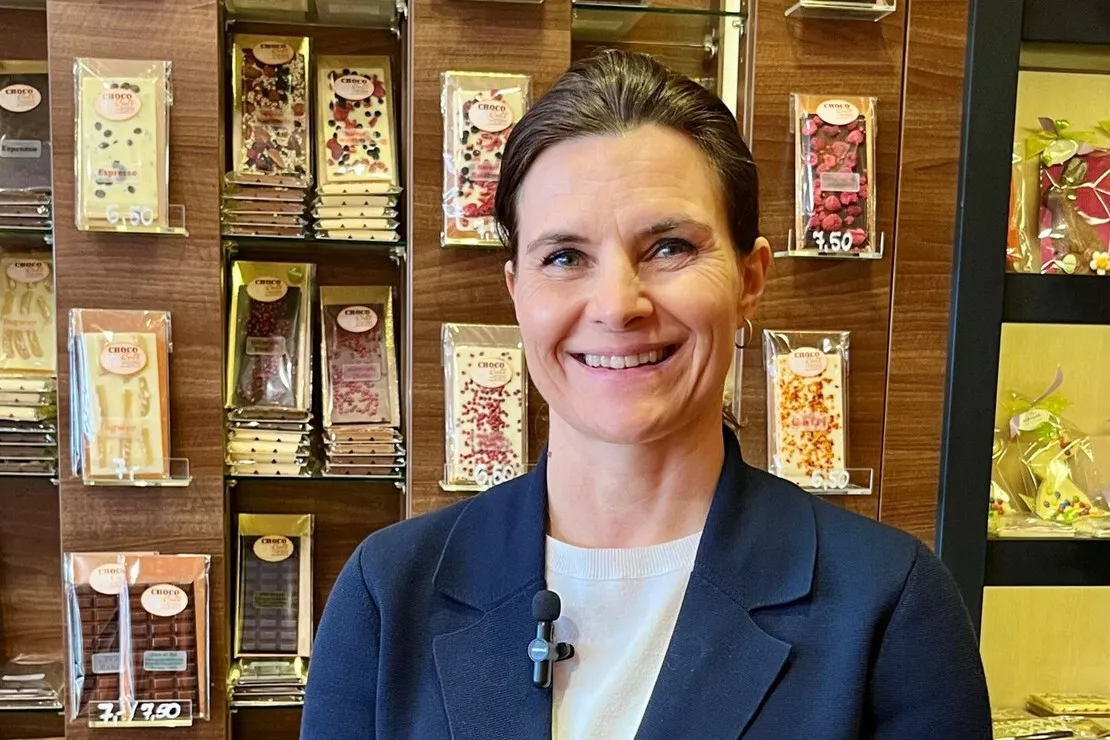 Tafelschokoladen, Eis und Pralinen verkaufen die Mangolds in einem kleinen Raum neben dem Café. Konditormeisterin Cornelia Mangold vor der Wand, die nur einen Teil des Angebots abbildet.