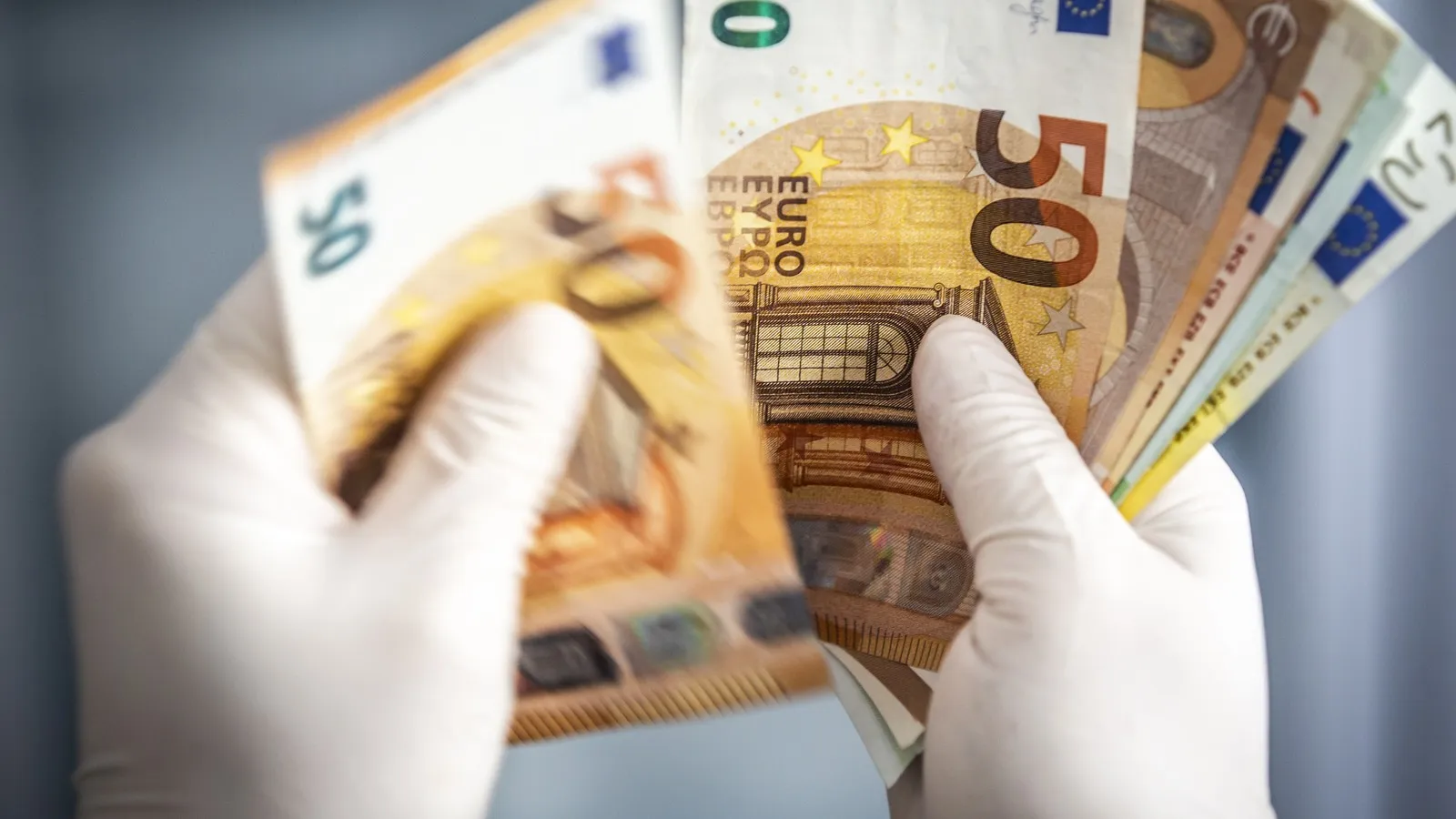 Hände mit Handschuhen halten Geldscheine