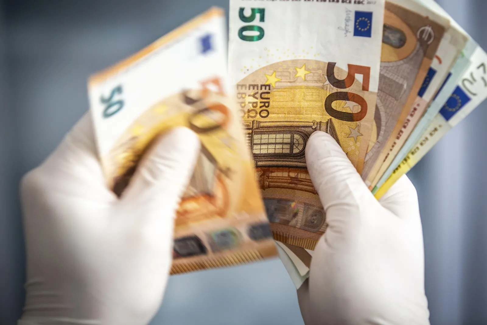 Hände mit Handschuhen halten Geldscheine