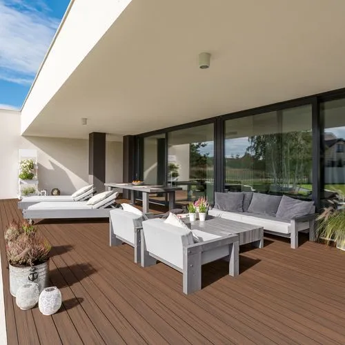 Eine Terrasse mit weißen Möbeln und herbstbraunen Dielen.