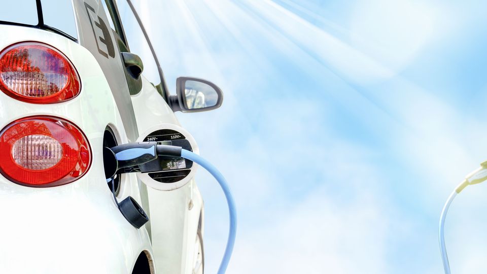 E-Auto wird beim schönem Wetter und blauem Himmel geladen.