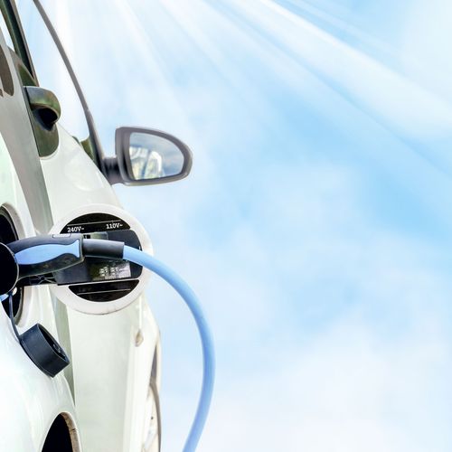 E-Auto wird beim schönem Wetter und blauem Himmel geladen.