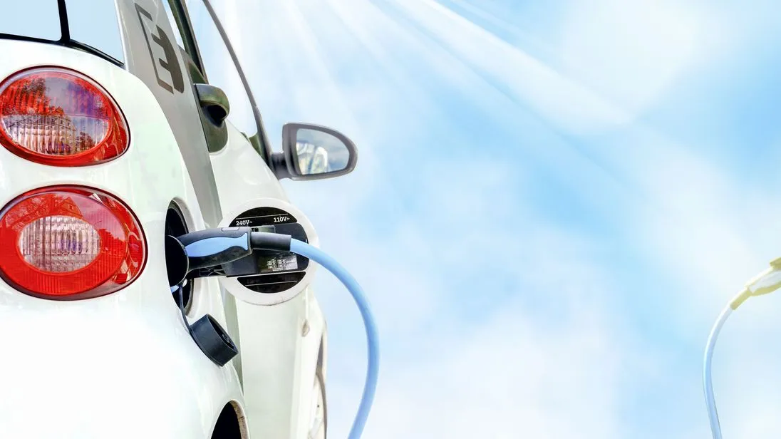 E-Auto wird beim schönem Wetter und blauem Himmel geladen.