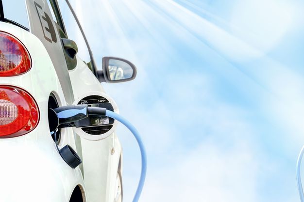 E-Auto wird beim schönem Wetter und blauem Himmel geladen.