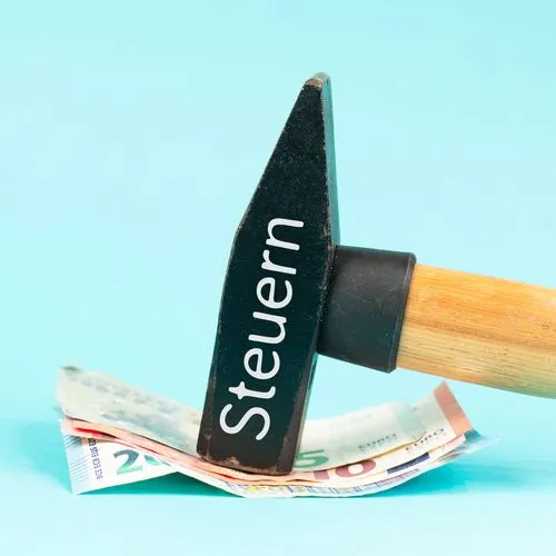 Hammer auf dem das Wort Steuern steht, fixiert ein Bündel Euro-Scheine.