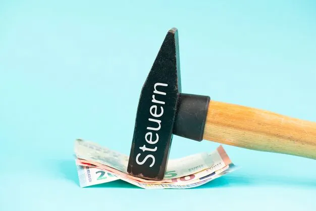 Hammer auf dem das Wort Steuern steht, fixiert ein Bündel Euro-Scheine.