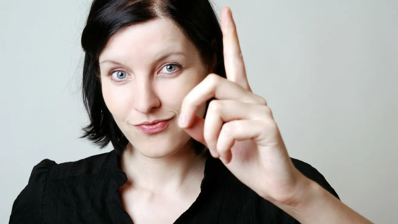 Frau erhebt ihren Zeigefinger.